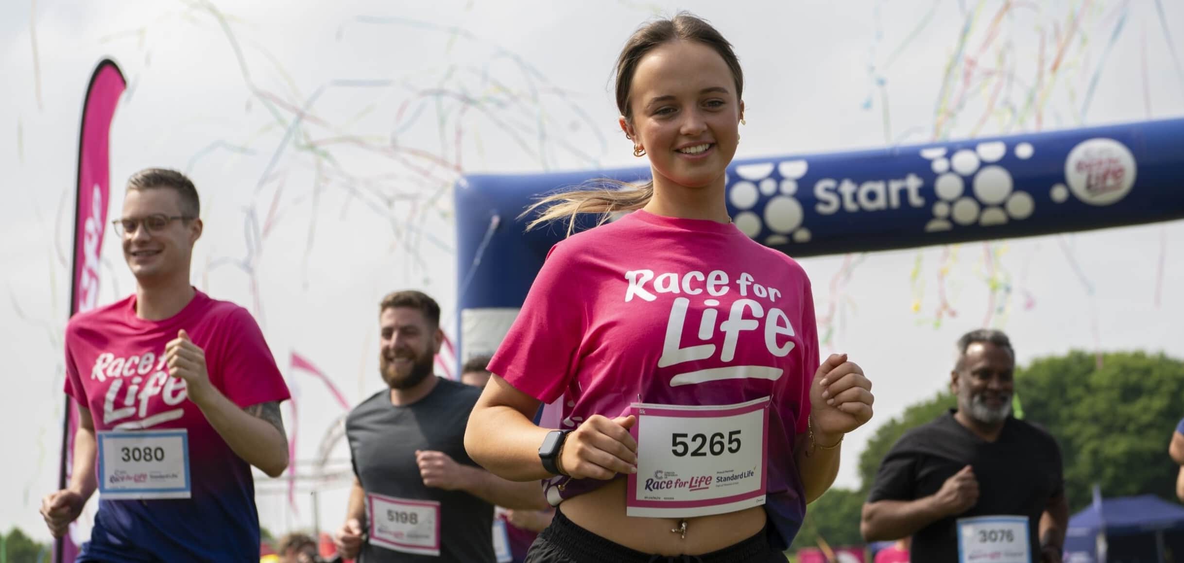 Women wearing pink race for life tshirt and start line of race for life event.